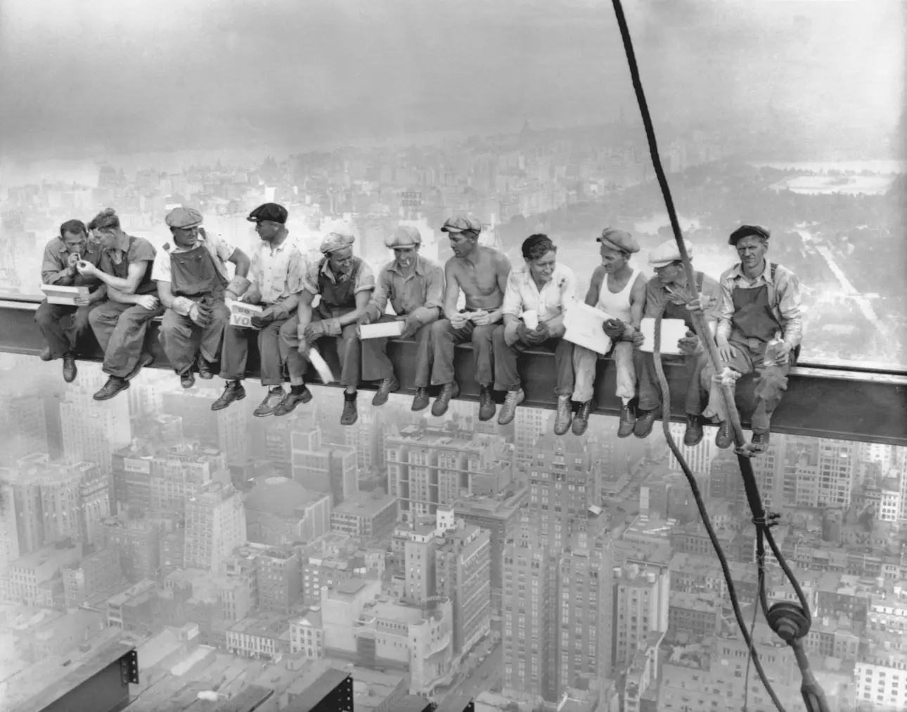 Construction workers eating lunch on a steel beam above New York City